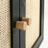 [Black] close-up of two cylindrical oak knobs paired on the centre stile between woven rattan door panels