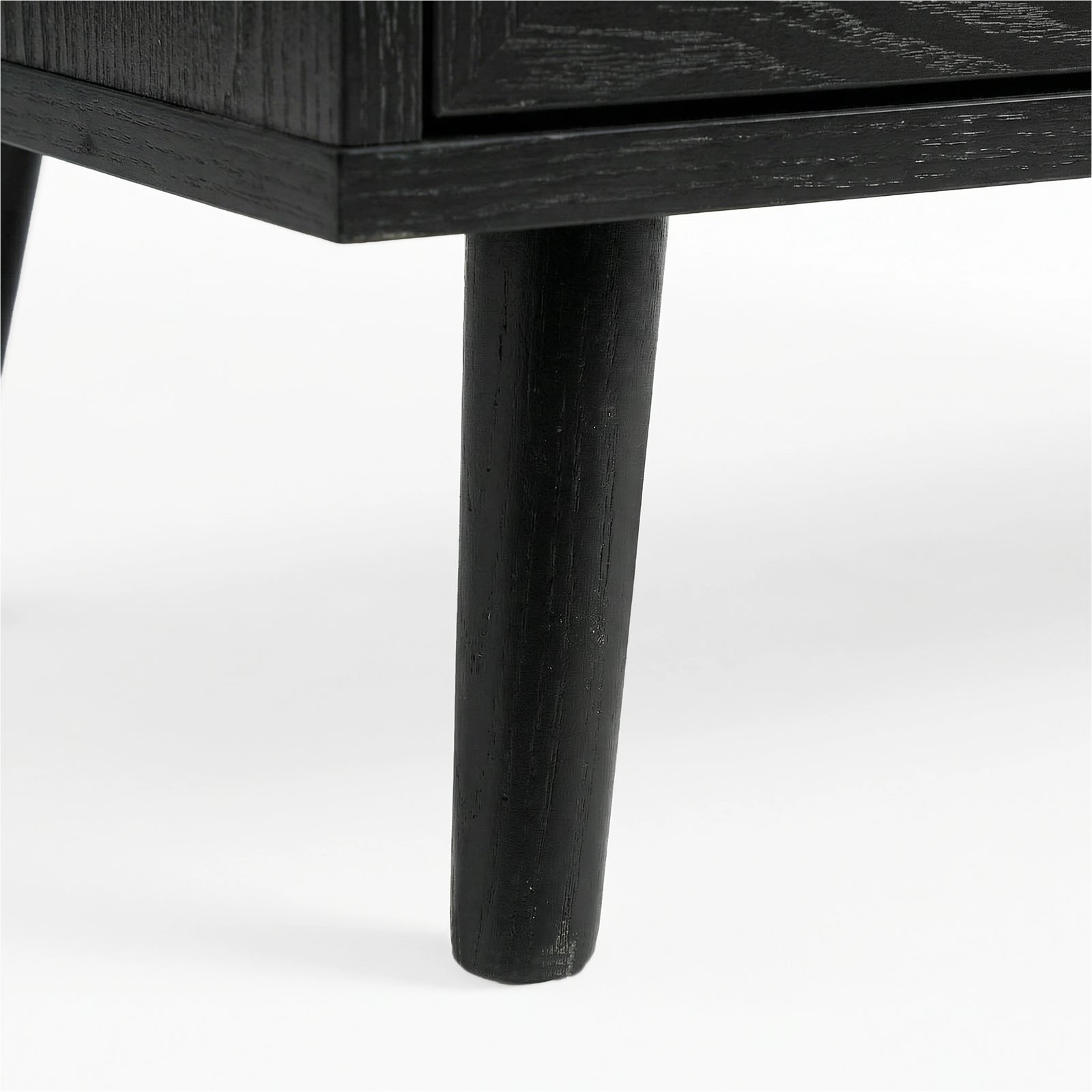 [Black] Wovena rattan TV unit leg macro, splayed black timber leg under the dark melamine cabinet edge