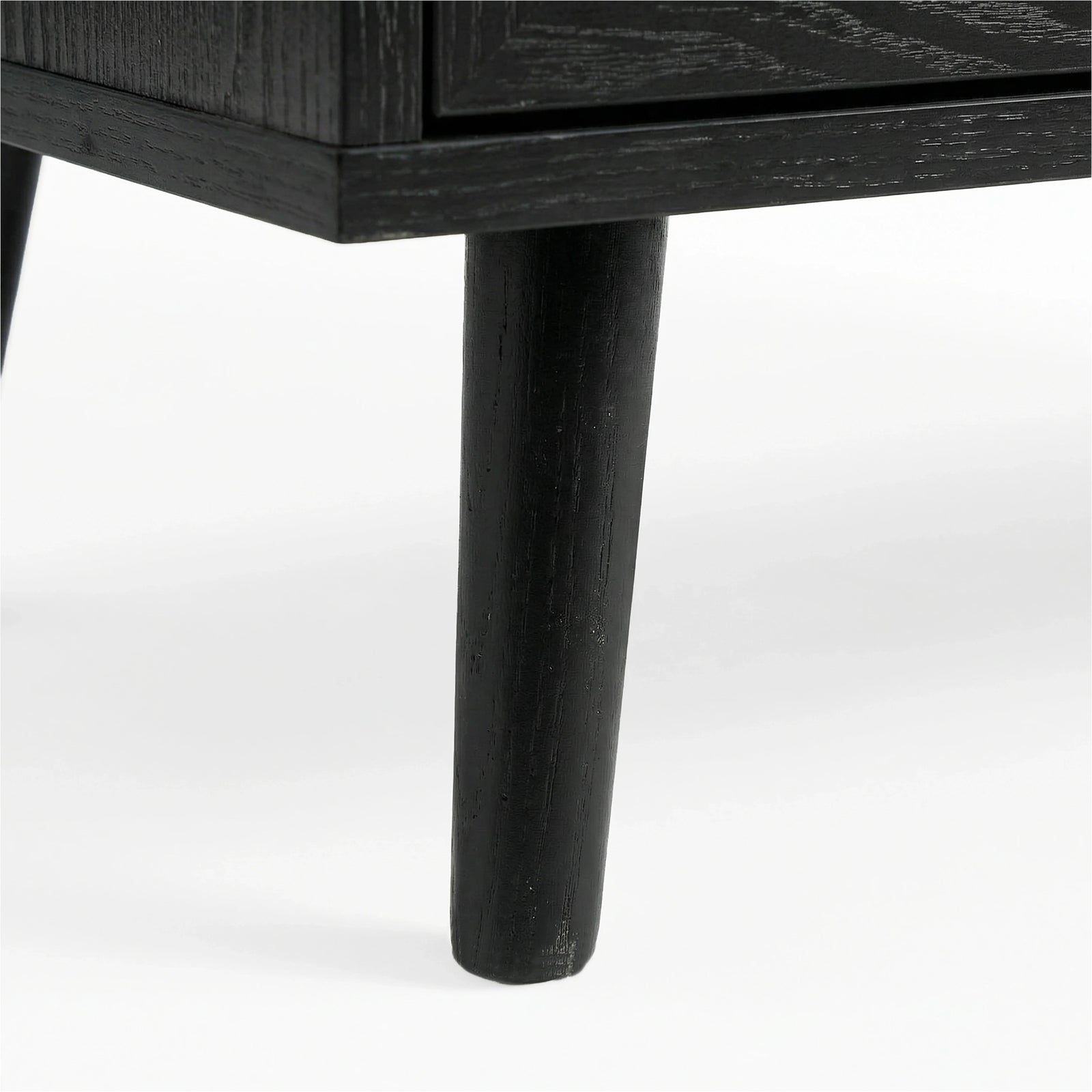 [Black] Wovena rattan TV unit leg macro, splayed black timber leg under the dark melamine cabinet edge