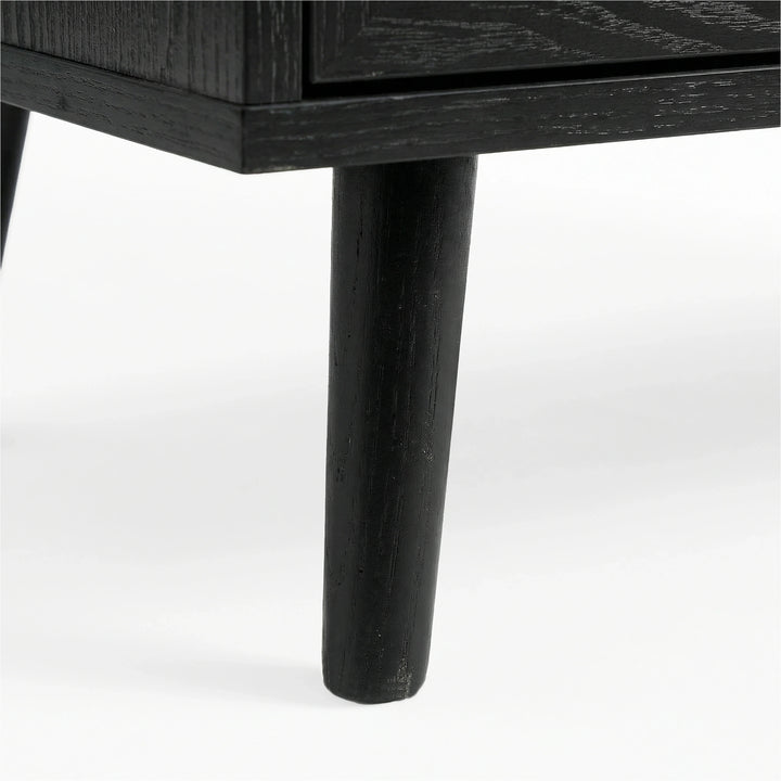 [Black] Wovena rattan TV unit leg macro, splayed black timber leg under the dark melamine cabinet edge