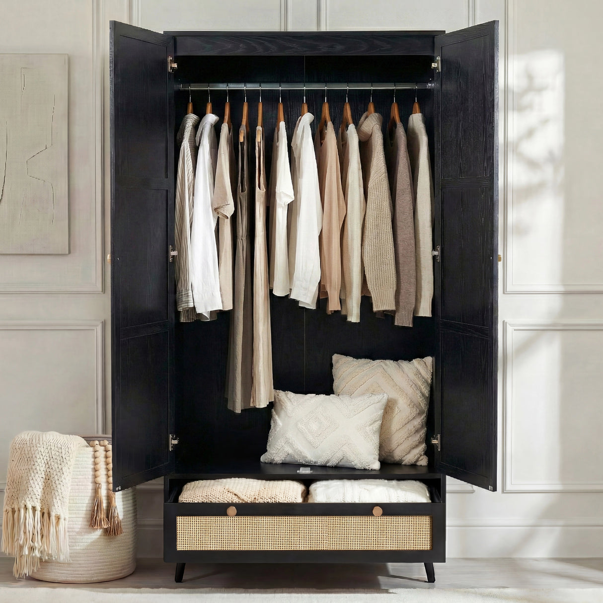 [Black] Wardrobe doors open showing hanging rail with clothes and open bottom drawer in styled room