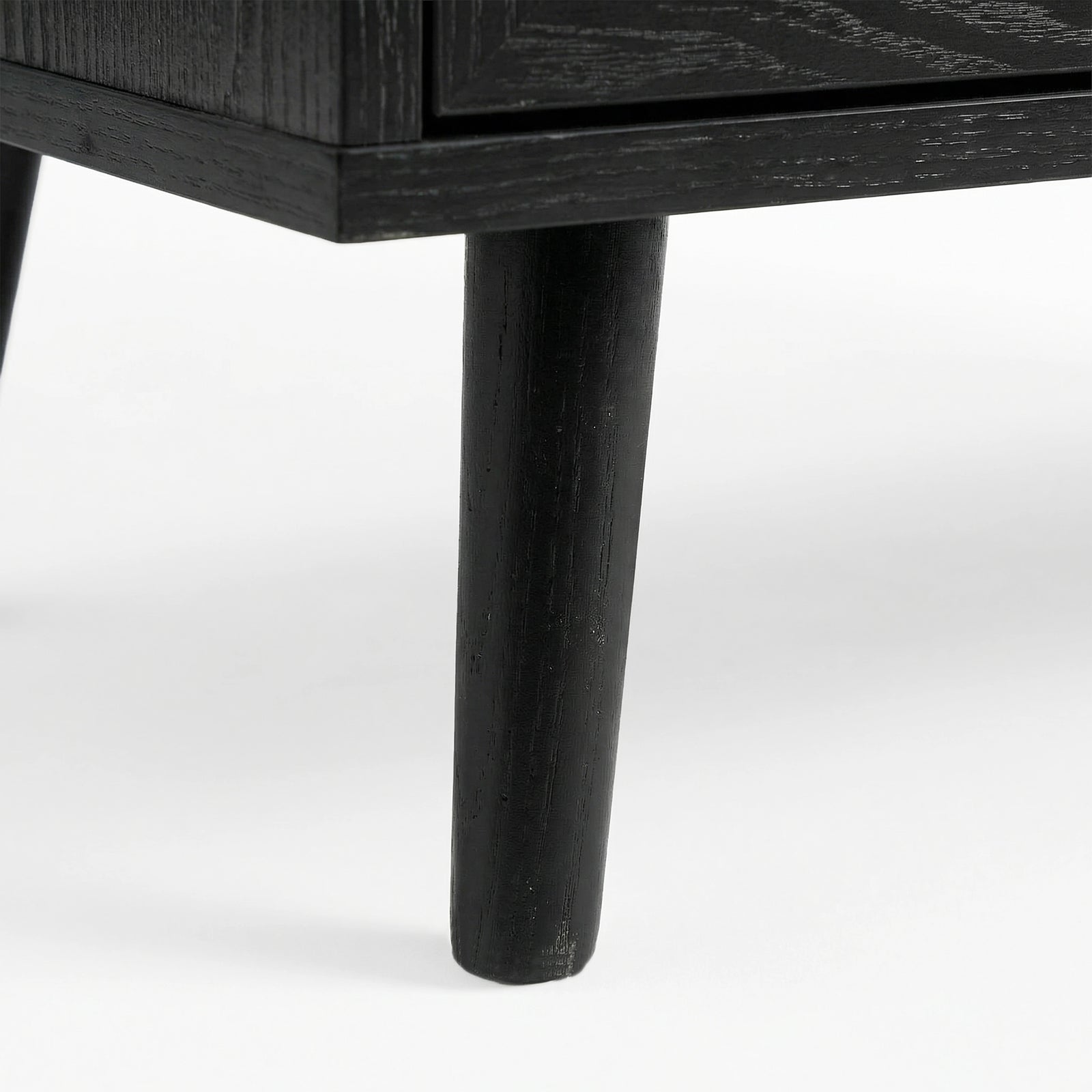 [Black] Underside corner of the black rattan wardrobe showing a single round splayed leg lifting the cabinet