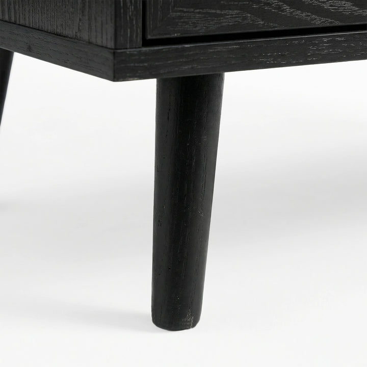 [Black] Underside corner of the black rattan wardrobe showing a single round splayed leg lifting the cabinet