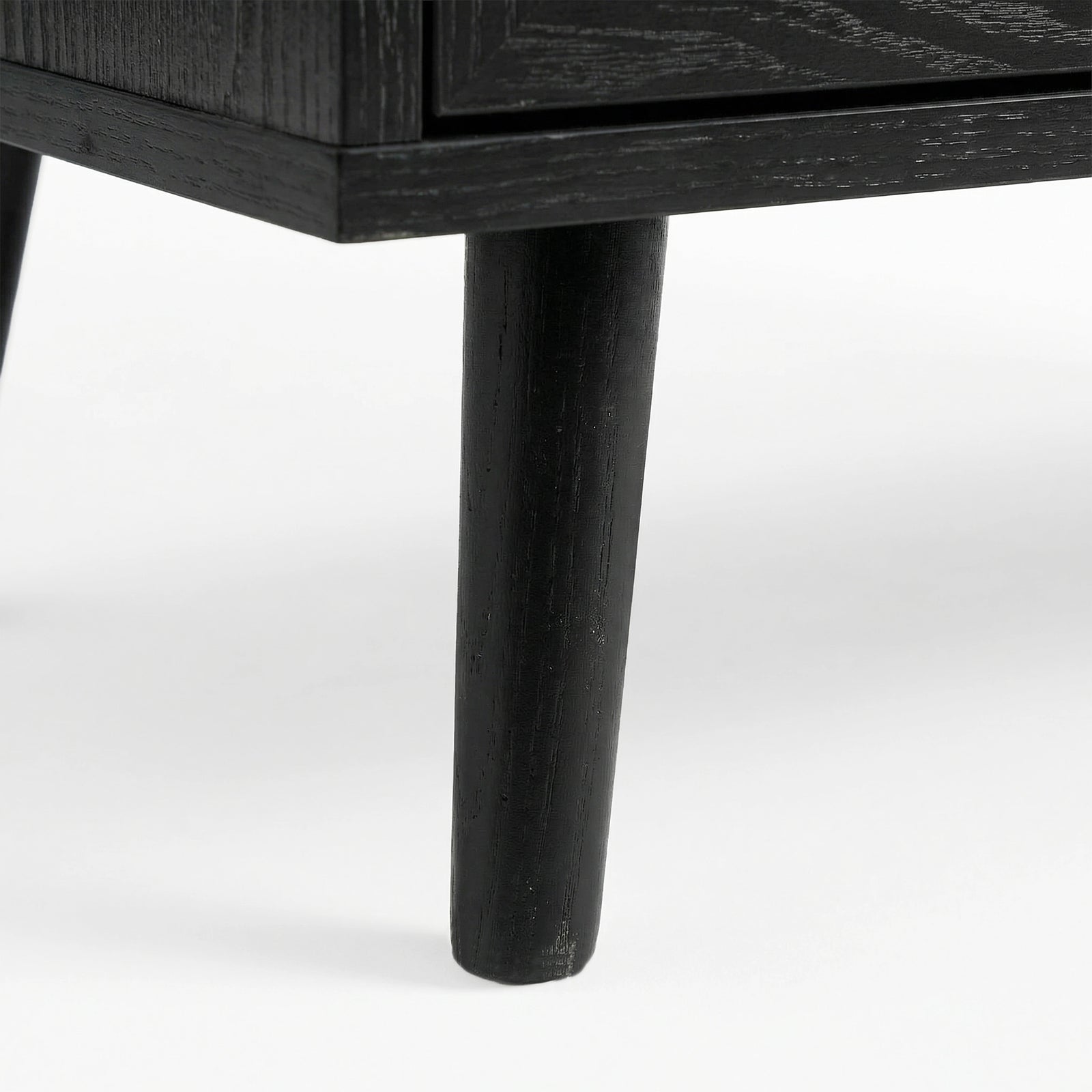 [Black] Underside corner of the black rattan wardrobe showing a single round splayed leg lifting the cabinet