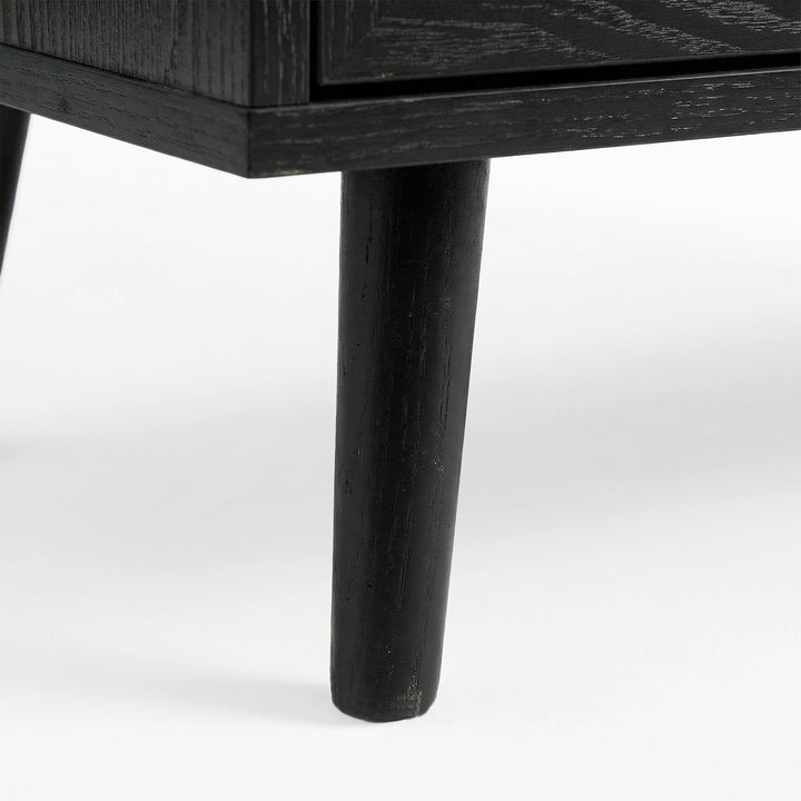 [Black] Underside corner of the black rattan wardrobe showing a single round splayed leg lifting the cabinet