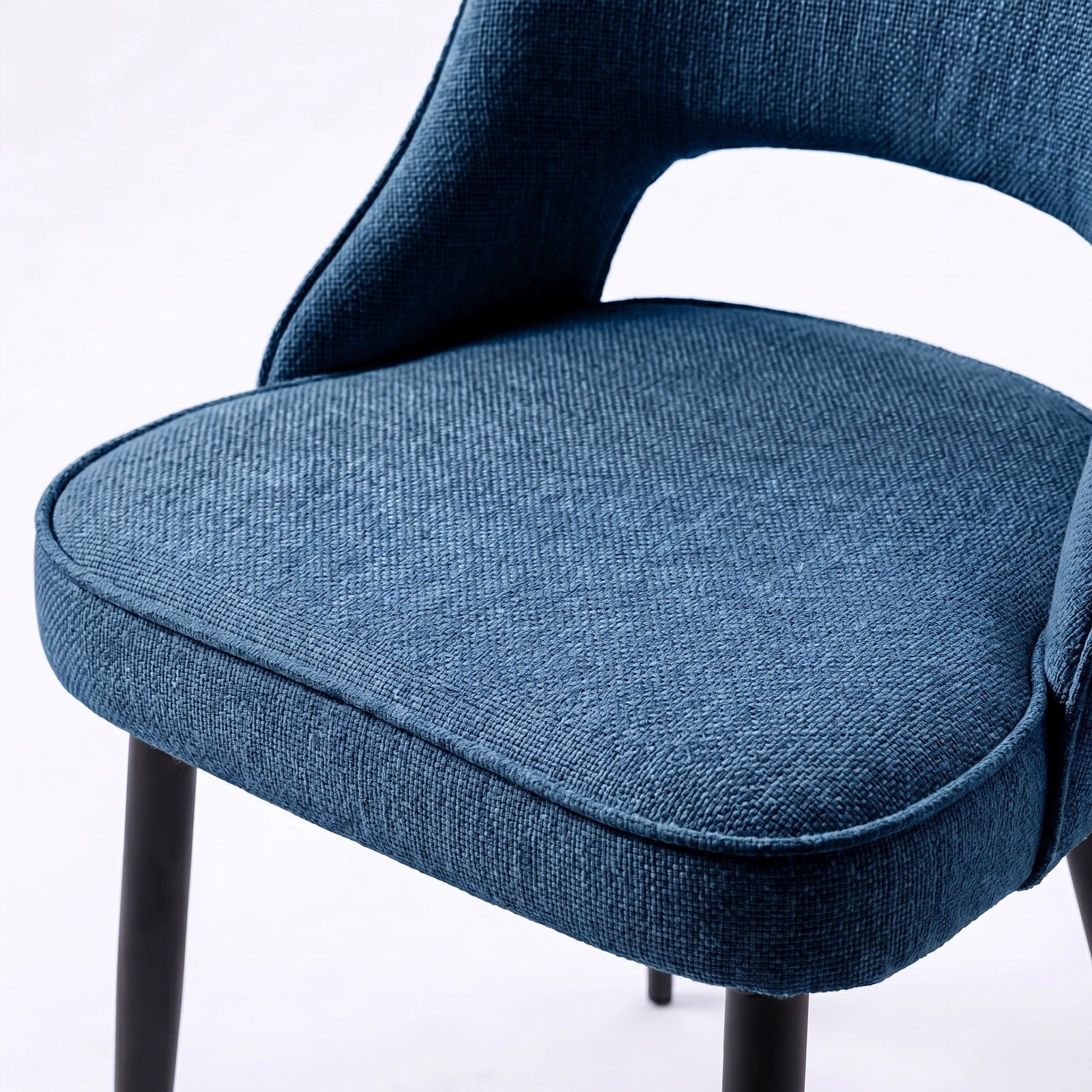 [Blue | Set of 4] Comfy dining chair close-up view of padded seat, piped edge, curved open back and black metal legs