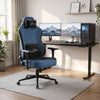 [Blue] ergonomic gaming office chair with black accents and a headrest pillow, positioned in front of a black computer desk setup with dual monitors in a bright home office