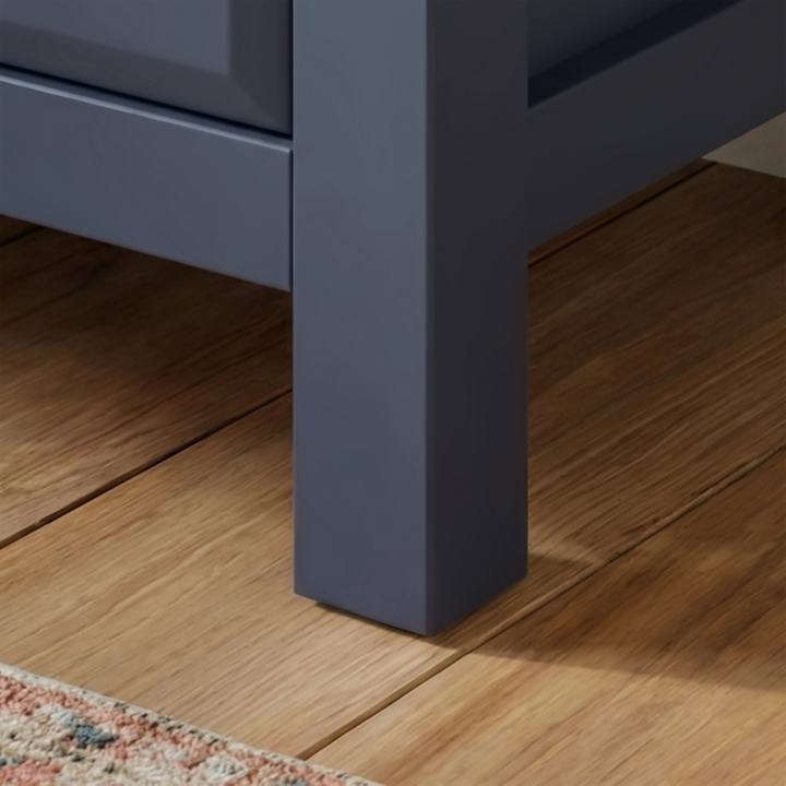 [Blue] Haven chest close-up of the solid square navy painted leg resting on warm straight oak plank floorboards