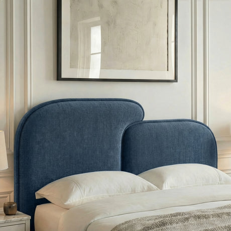 Close detail of a curved, padded headboard upholstered in textured blue fabric of a king size bed frame