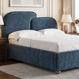 [King | Blue] upholstered bed frame with a tall curved headboard and matching footboard, shown in a styled bedroom setting with white bedding, bedside tables, lamps, and a rug.