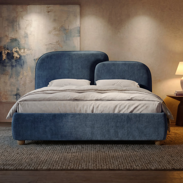 [King | Blue] Front-facing view of a blue bed with padded headboard, centered between bedside tables and warm lamps
