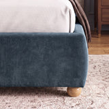 [King | Blue] Lower corner of a blue fabric bed frame with rounded edges and small wooden legs placed on wooden flooring