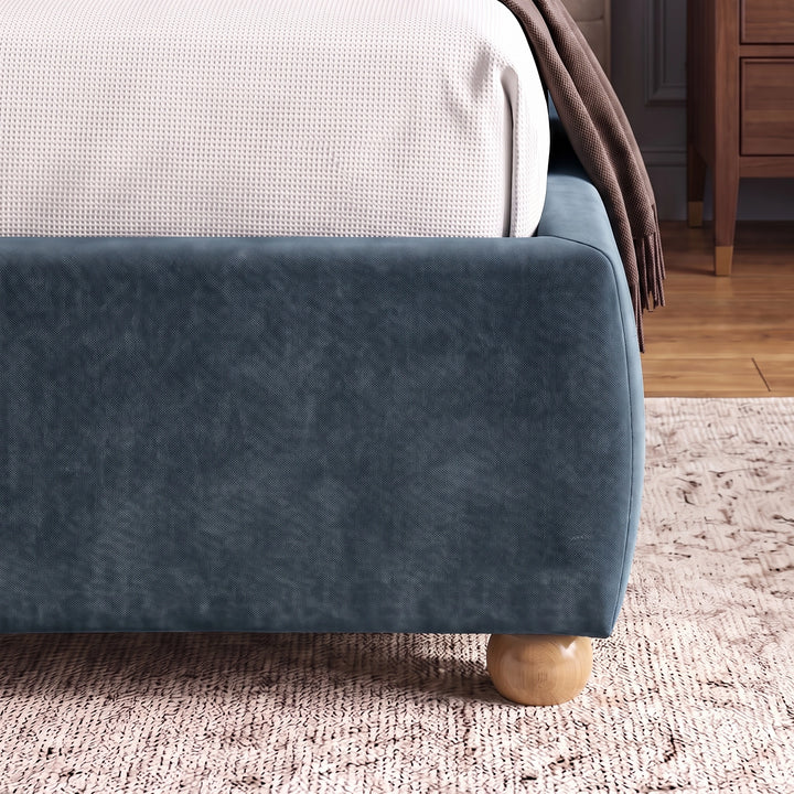 [King | Blue] Lower corner of a blue fabric bed frame with rounded edges and small wooden legs placed on wooden flooring