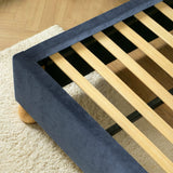 Close view of evenly spaced wooden slats set inside a blue upholstered king size bed frame for mattress support