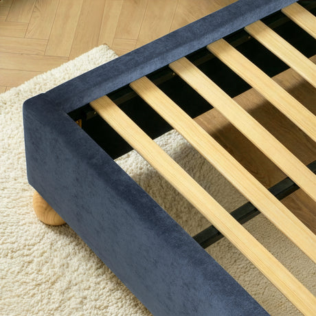 Close view of evenly spaced wooden slats set inside a blue upholstered king size bed frame for mattress support