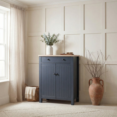 [Blue] Linra shoe cabinet with grooved double doors, oak top, black knobs, and top drawer in a bright panelled hallway corner