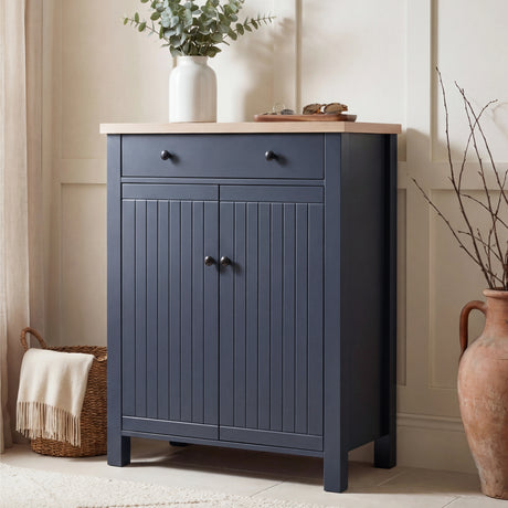 [Blue] Linra shoe cabinet front-facing with grooved double doors, top drawer, oak top, and black knobs in a warm hallway