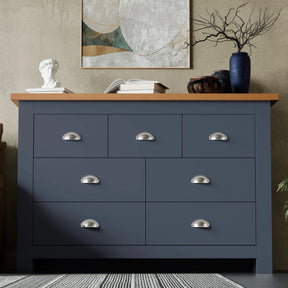[Blue] Shaker 7 drawer wide chest with oak top cup handles and abstract art on textured wall.