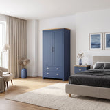 [Blue] wardrobe with a oak wood veneer top and silver handles, shown in a styled bedroom next to a bed and nightstand.