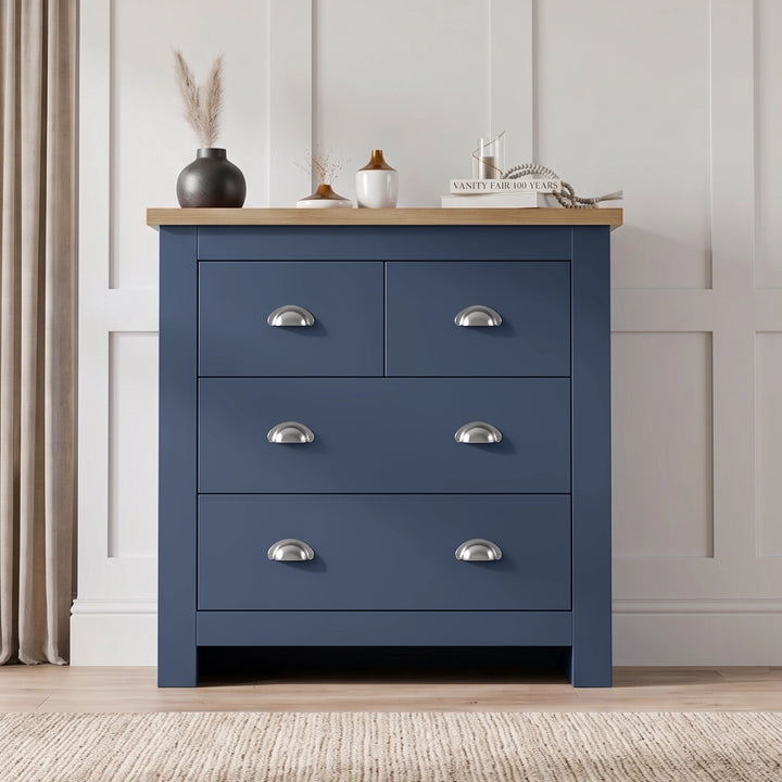[Blue] Four drawer chest front view with oak top, chrome cup handles, vase, books, curtains, and panelled wall