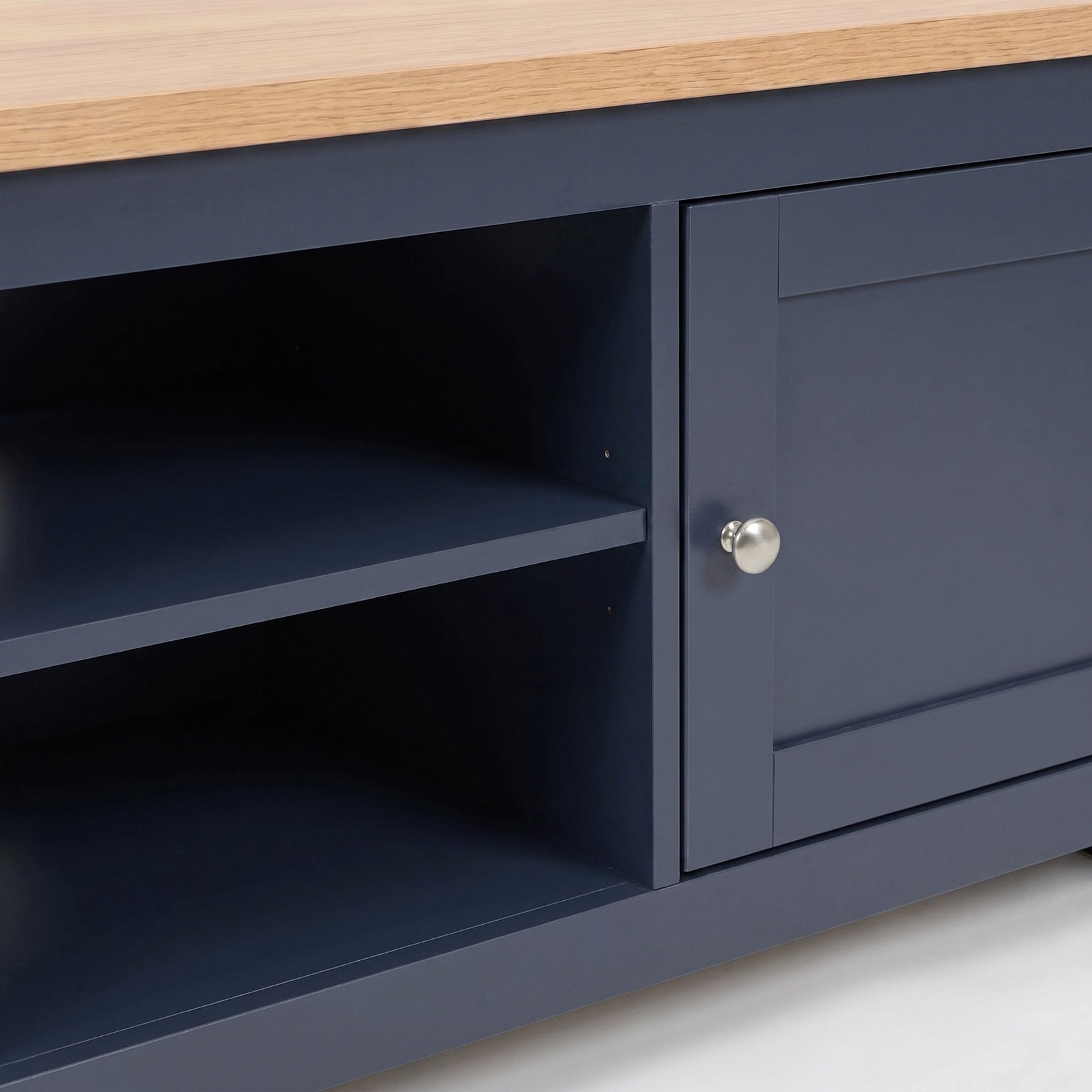 [Blue] Close-up of a tv unit with a light oak wood top, featuring a single cabinet door with a silver round knob and open shelving on the left.