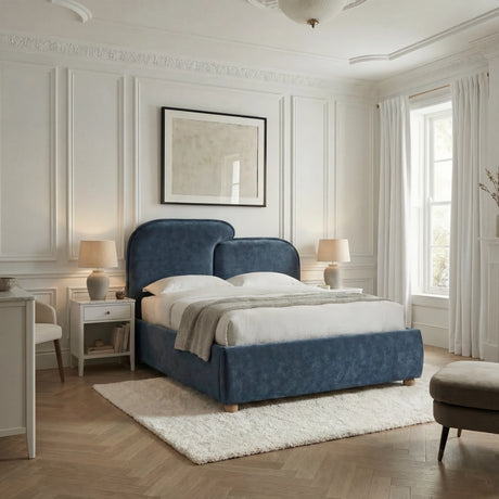 Wide room view showing a blue upholstered bed frame centered on a rug within a softly lit bedroom