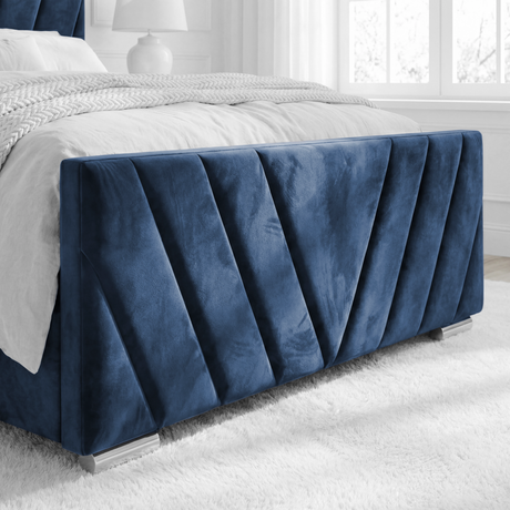 Close-up of the footboard of the blue velvet ottoman bed, showing its elegant design and smooth upholstery