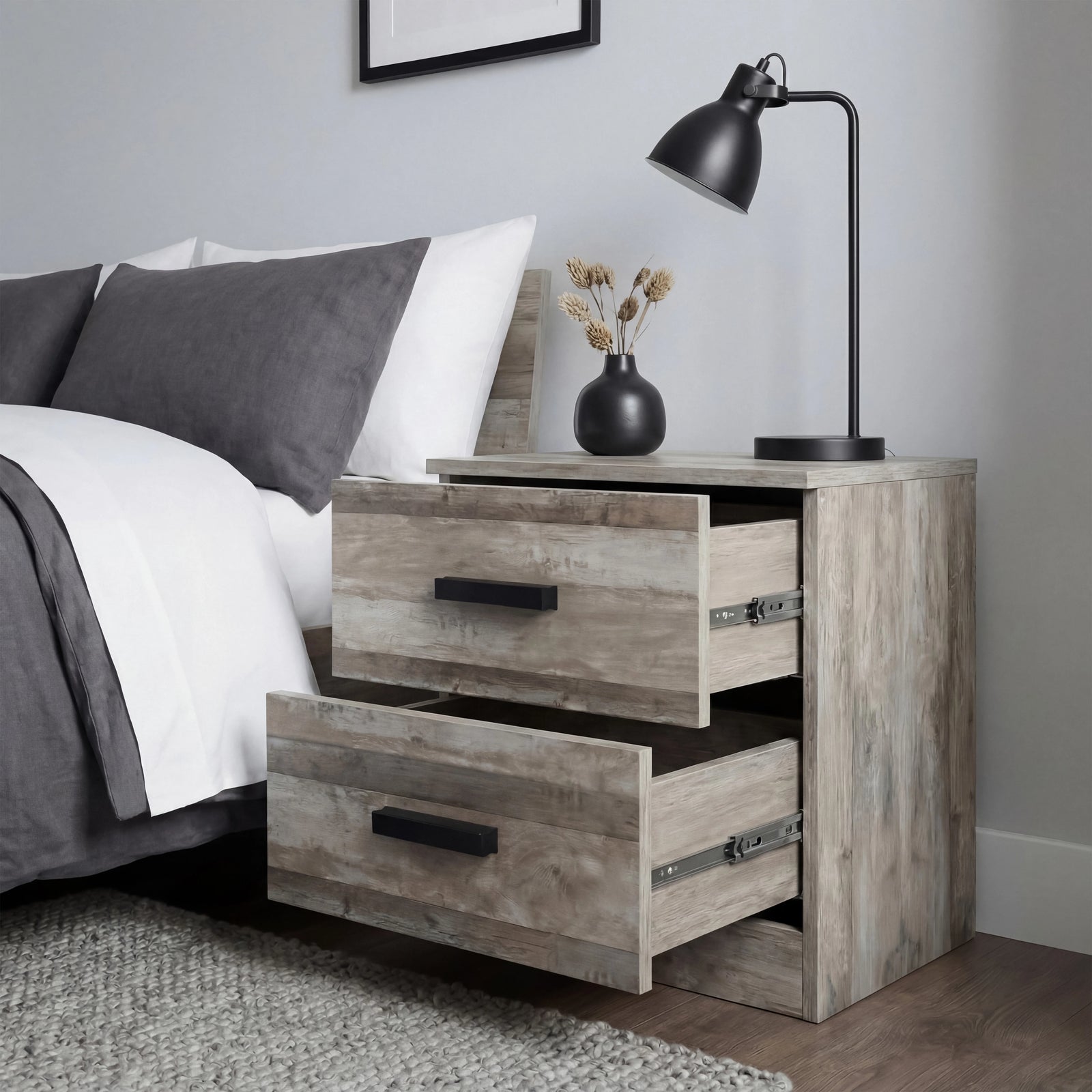[Ash Grey] Blythe bedside table with upper and lower drawers pulled out at different depths next to bed and desk lamp