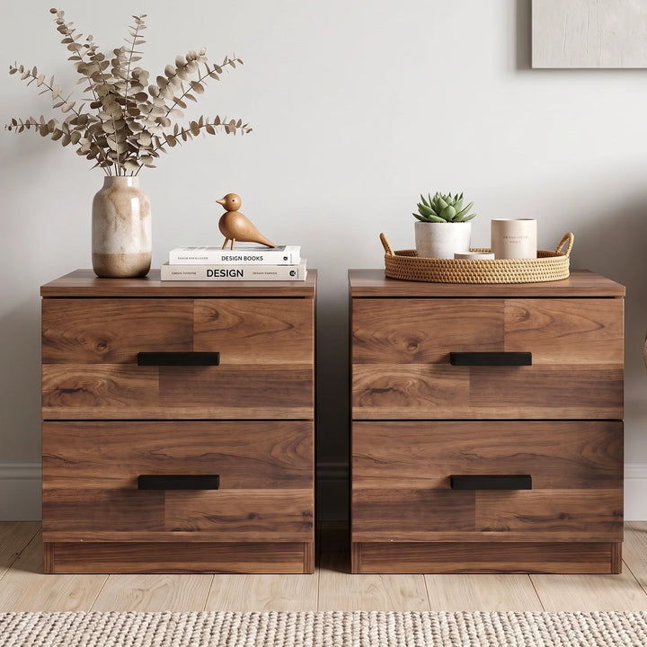[Dark Bronx] Two drawer nightstands with dark metal handles, styled in a bright room with plants, a vase of dried flowers, and a small basket on top.