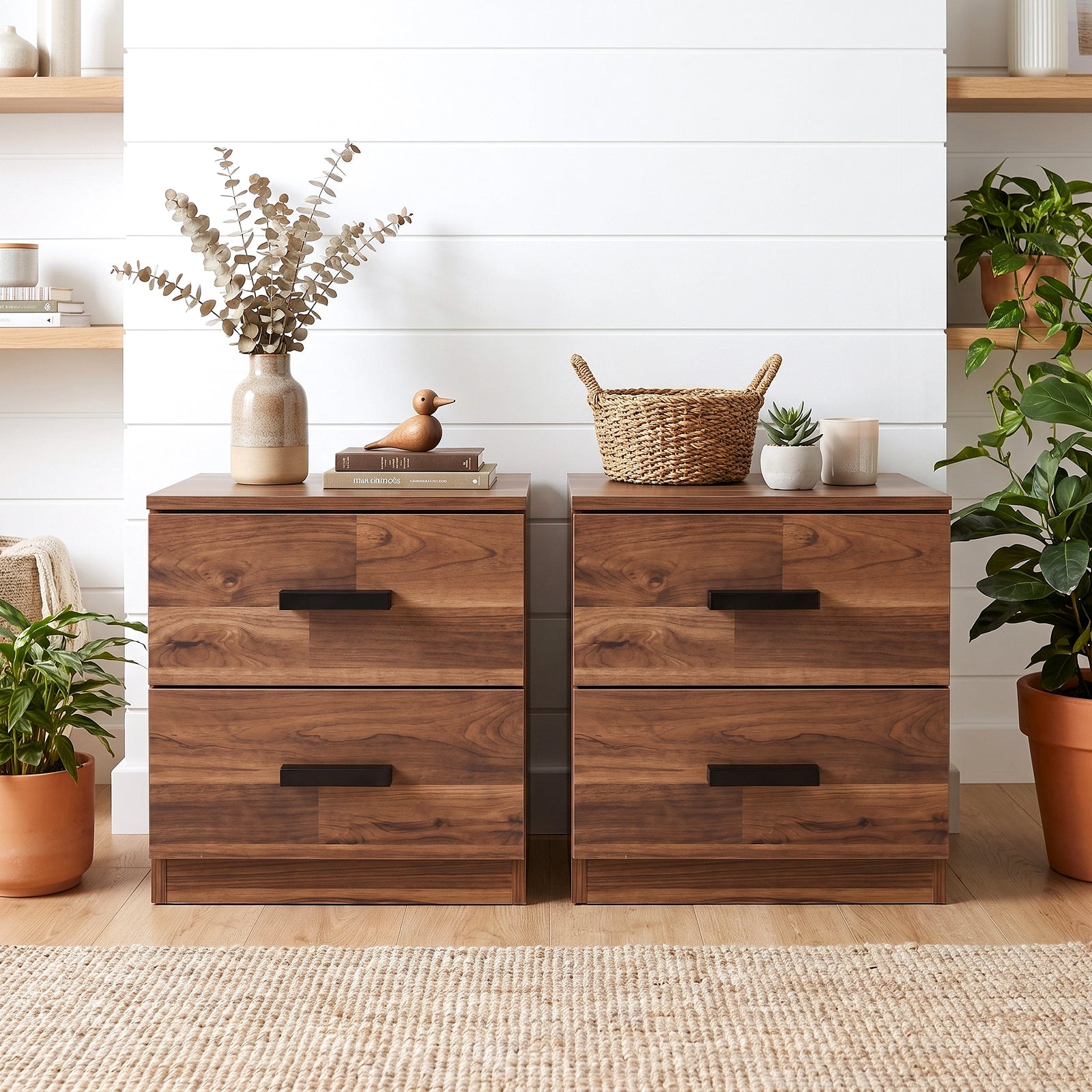 [Dark Bronx] Two drawer nightstands with dark metal handles, styled in a bright room with plants, a vase of dried flowers, and a small basket on top.