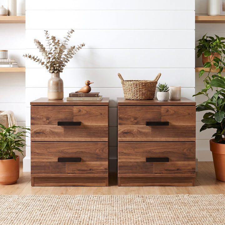 [Dark Bronx] Two drawer nightstands with dark metal handles, styled in a bright room with plants, a vase of dried flowers, and a small basket on top.