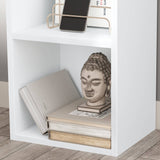 Close-up of lower shelf on Blisswood white bookcase, styled with books and decorative Buddha head.