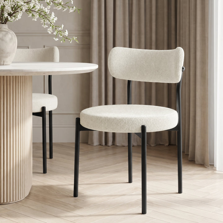 [Cream | Set of 4] Single boucle dining chair with rounded seat, curved back and slim black metal legs beside a round table.