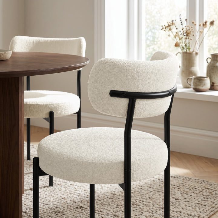 [Cream | Set of 4] lifestyle view of boucle dining chair with curved backrest and black metal frame.