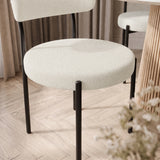 [Cream | Set of 4] Close-up of boucle dining chair round padded seat, curved back and black metal legs.