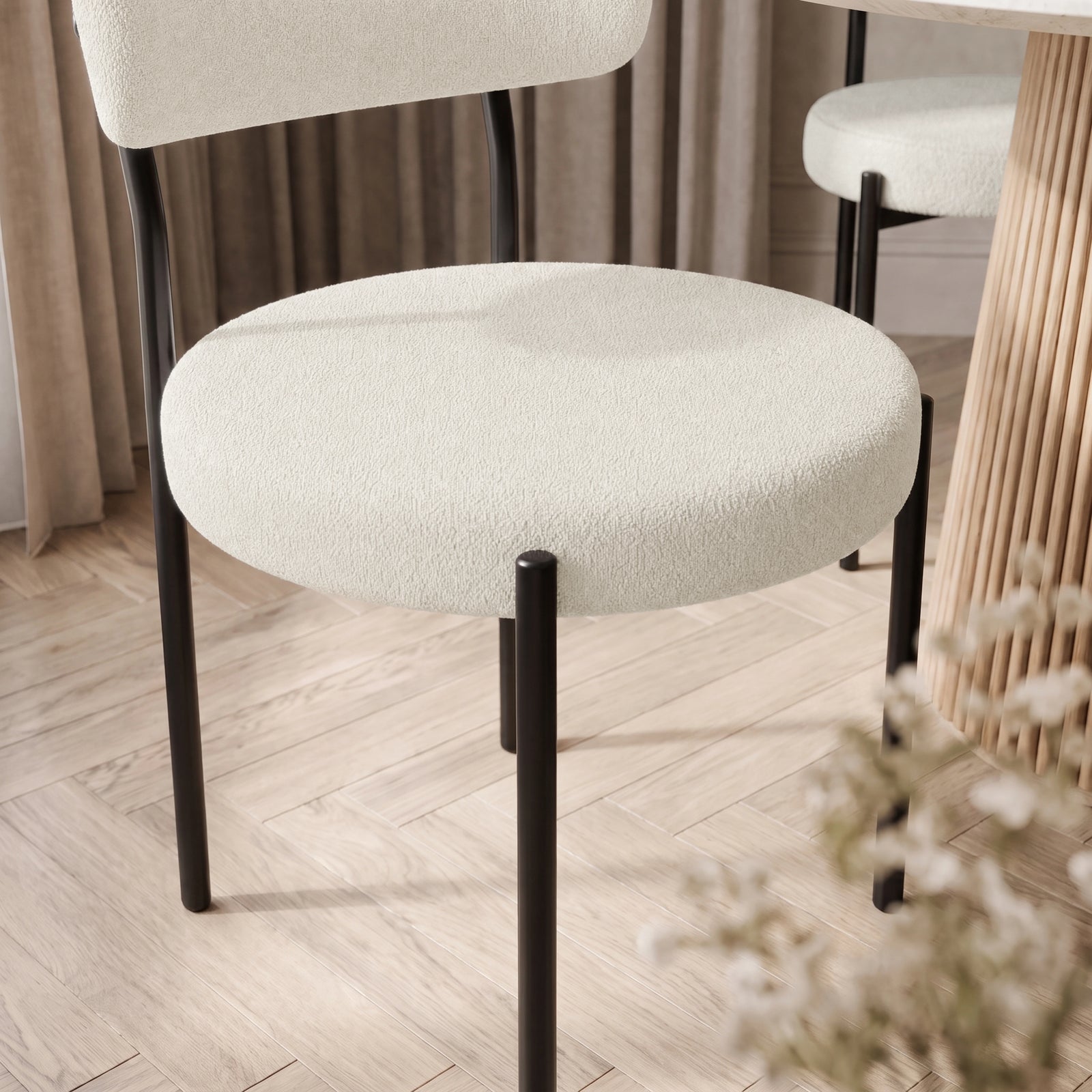 [Cream | Set of 4] Close-up of boucle dining chair round padded seat, curved back and black metal legs.