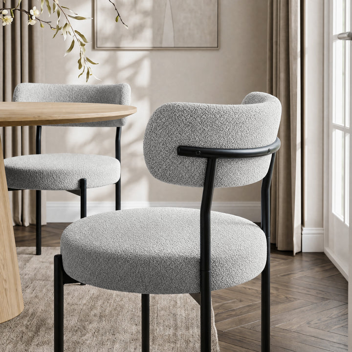 [Light Grey | Set of 4] Rear lifestyle view of boucle dining chair with curved backrest and black metal frame.