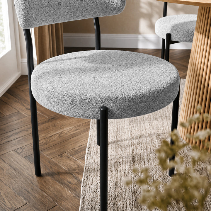 [Light Grey | Set of 4] Close-up of boucle dining chair round padded seat, curved back and black metal legs.
