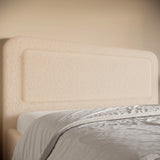 Beige upholstered headboard with a bed partially visible