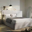 Grey boucle double ottoman bed angled, charcoal tasselled throw draped over foot of low storage base