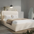 Wide angle of beige boucle king ottoman bed, gas-lift base with folded striped throw across foot