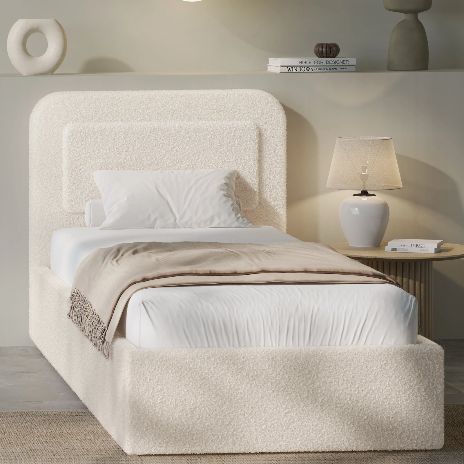 Beige boucle single ottoman bed angled view, rounded pill headboard beside fluted lamp and pebble vase shelf