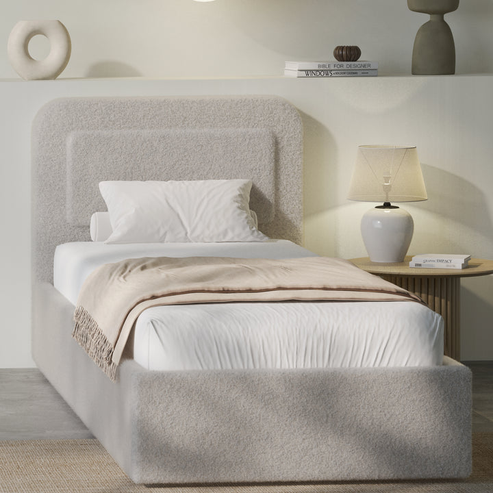 Grey boucle single ottoman bed angled, soft greige pill headboard and gas-lift base with beige throw