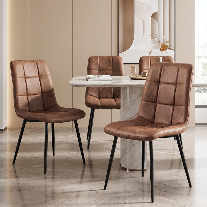 [Brown] Three suede dining chairs around a pale stone-effect table, showing tufted fronts and slim black legs.