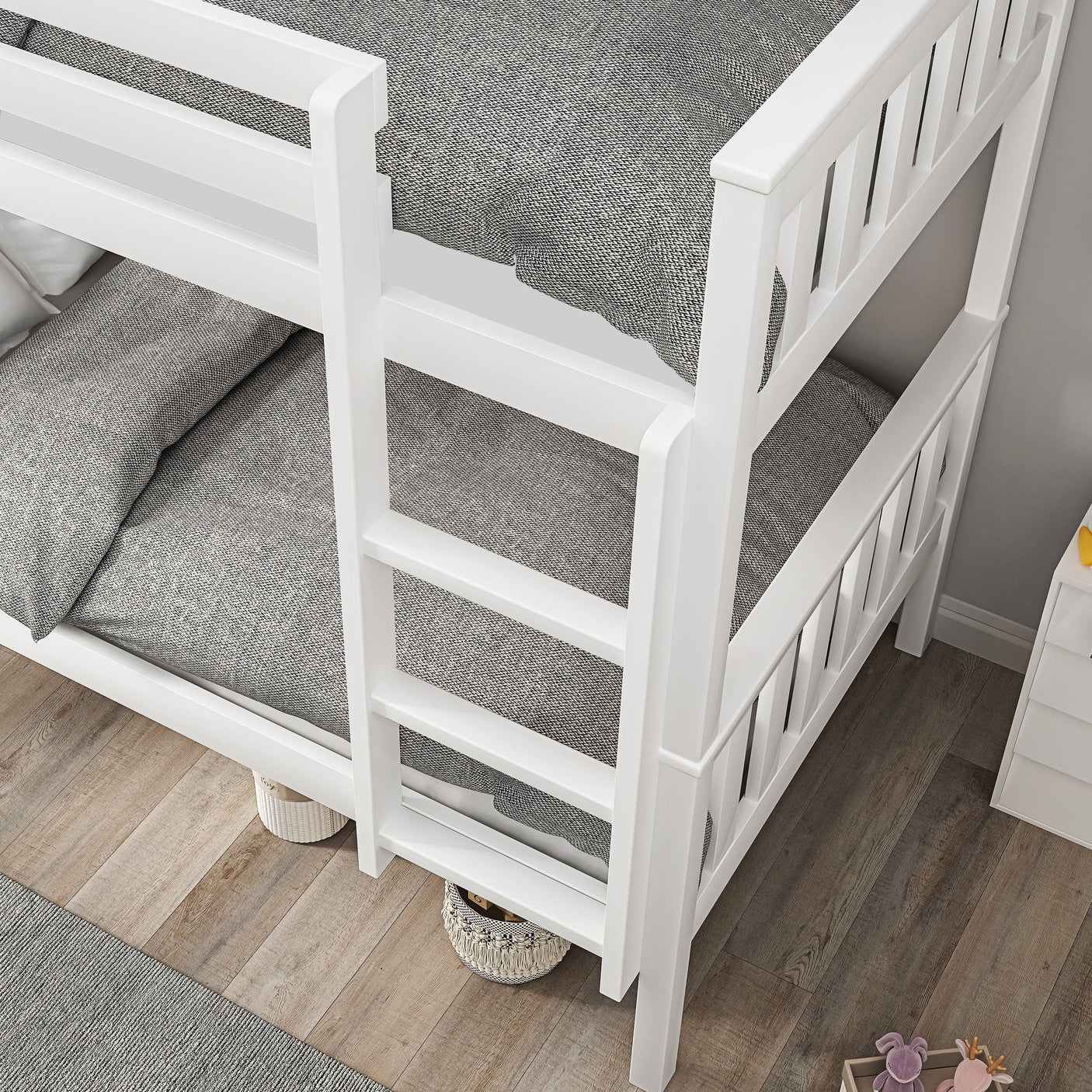 Close-up of white bunk bed ladder and under-bed storage space with toy baskets, perfect for kids' room organization.