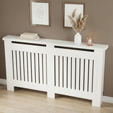 [Large] Chelsea White Radiator Cover angled three-quarter view in taupe room with two rose gold-framed art prints above and pampas vase and lantern on top