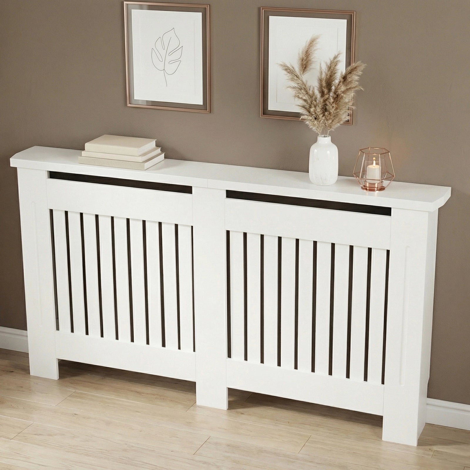 [Large] Chelsea White Radiator Cover angled three-quarter view in taupe room with two rose gold-framed art prints above and pampas vase and lantern on top