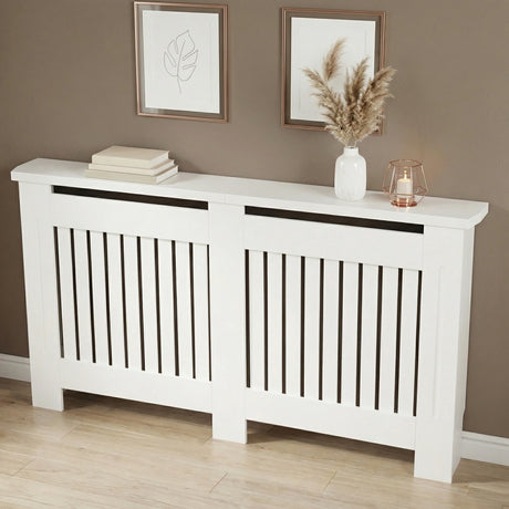 [Large] Chelsea White Radiator Cover angled three-quarter view in taupe room with two rose gold-framed art prints above and pampas vase and lantern on top