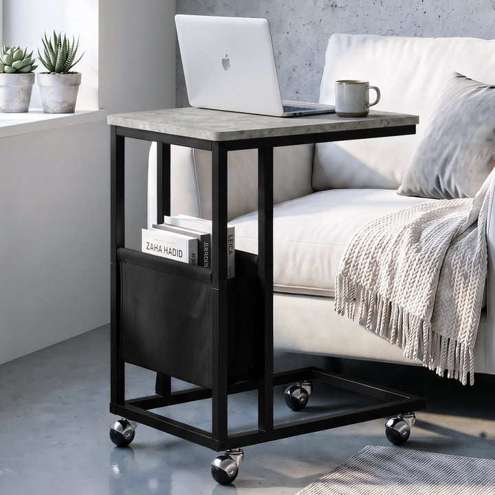 [Concrete] C-shaped side table by sofa with concrete-effect top, black frame, pouch, laptop and caster wheels