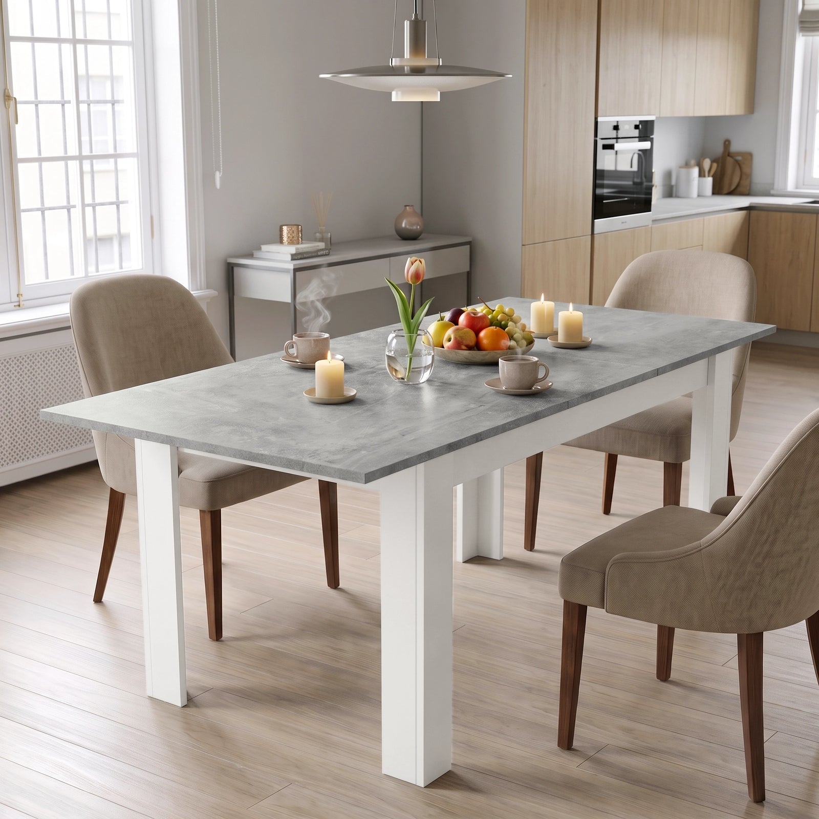 [Concrete] Closed concrete-effect dining table styled with fruit, flowers, and candles; beige chairs stand by its white legs.